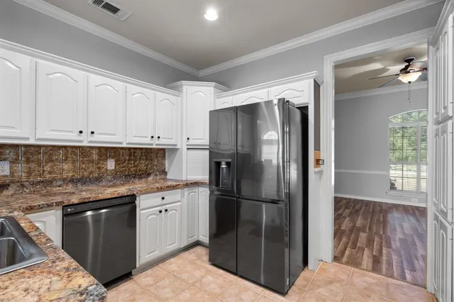 a kitchen with stainless steel appliances granite countertop a refrigerator a sink and white cabinets