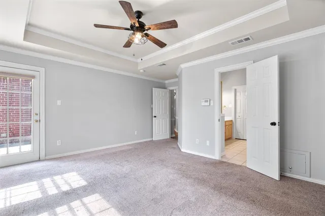 an empty room with chandelier fan and windows
