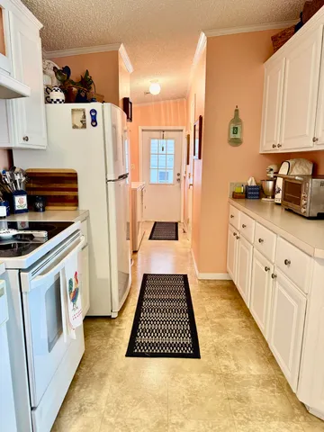 a kitchen with a sink a refrigerator and white cabinets
