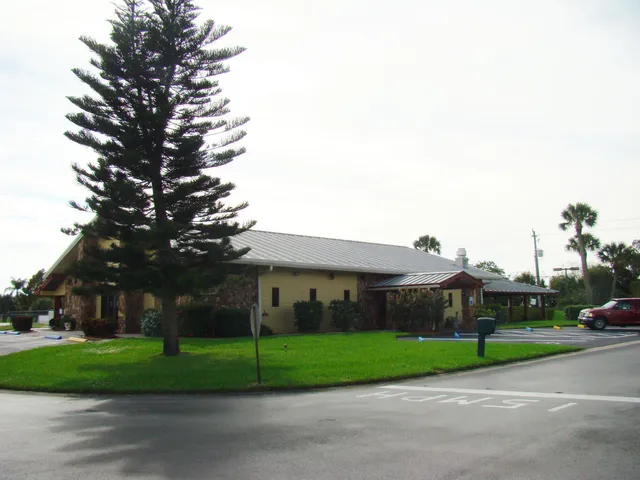 a view of a white house next to a yard with big trees