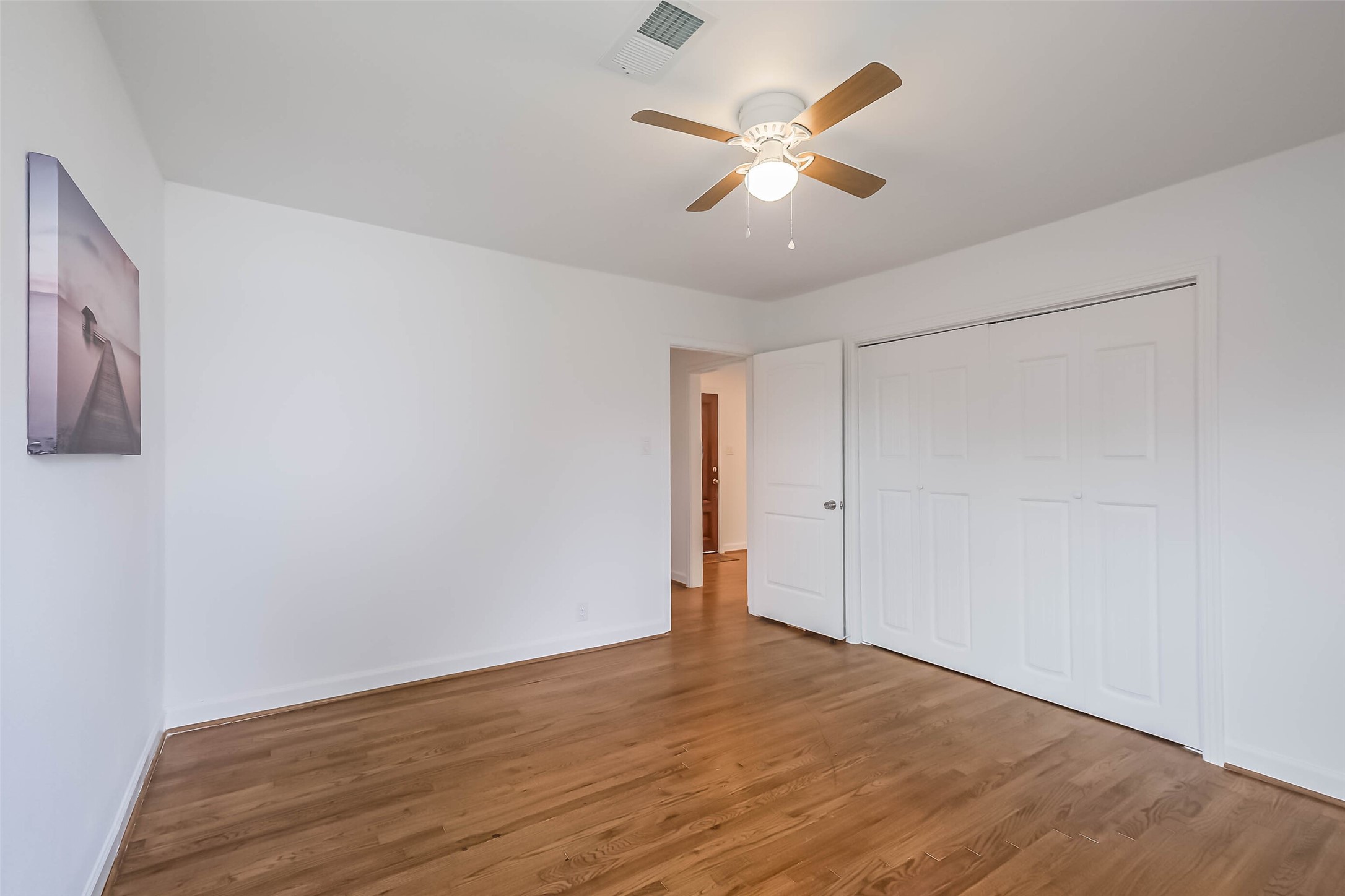 7543 Greenstone Street Houston, TX 77087 - Photo 11 of 24 an empty room with wooden floor and ceiling fan