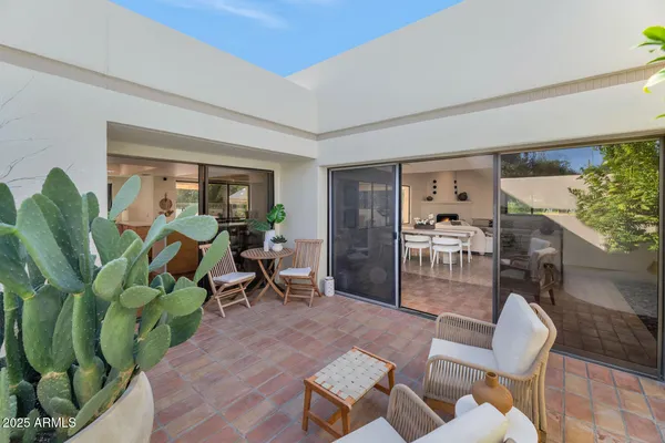 a living room with furniture a plant and a floor to ceiling window