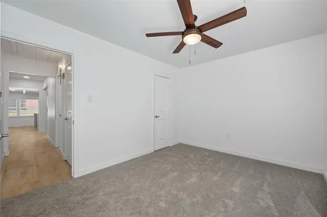 an empty room with a ceiling fan and carpet