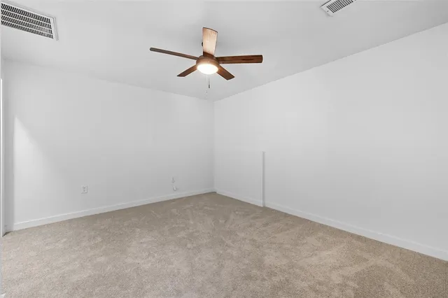 an empty room with a ceiling fan and window