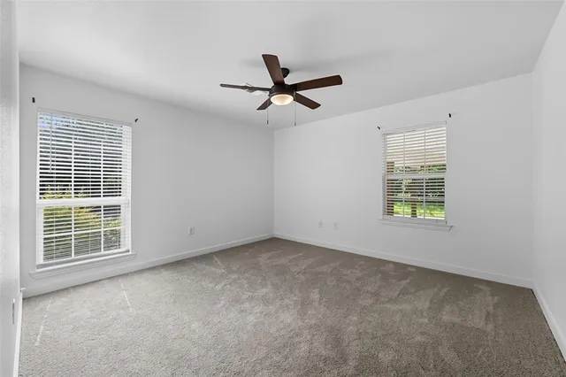 an empty room with windows and fan