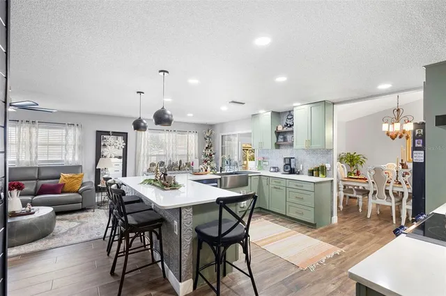 a kitchen with stainless steel appliances kitchen island granite countertop a dining table chairs stove a refrigerator and cabinets