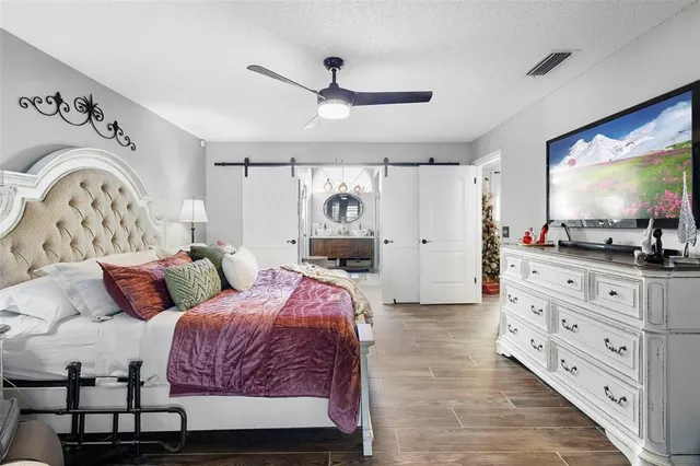 a spacious bedroom with a bed and a flat tv screen