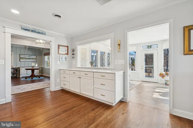 a large white kitchen with cabinets wooden floor and a sink