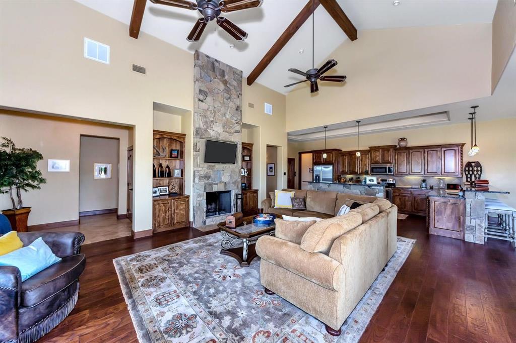 1231 Rawhide Ridge Graford, TX 76449 - Photo 14 of 26 Living room with ceiling fan, dark wood-type flooring, high vaulted ceiling, beamed ceiling, and a fireplace