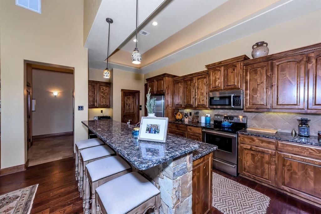 1231 Rawhide Ridge Graford, TX 76449 - Photo 17 of 26 Kitchen featuring hanging light fixtures, dark hardwood / wood-style flooring, dark stone countertops, a kitchen island, and appliances with stainless steel finishes