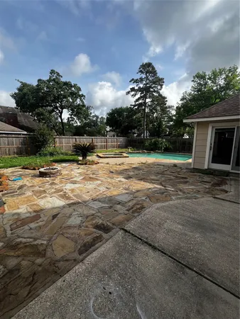 a backyard of a house with table and chairs plants and large trees