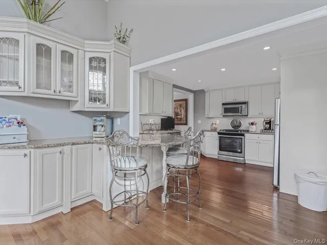 a living room with stainless steel appliances kitchen island granite countertop furniture and a wooden floor