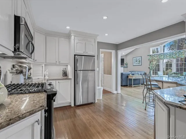 a kitchen with granite countertop a refrigerator stove and wooden floor