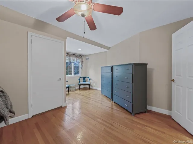 an empty room with wooden floor chandelier fan and windows