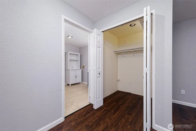 a view of a hallway with wooden floor and a bathroom