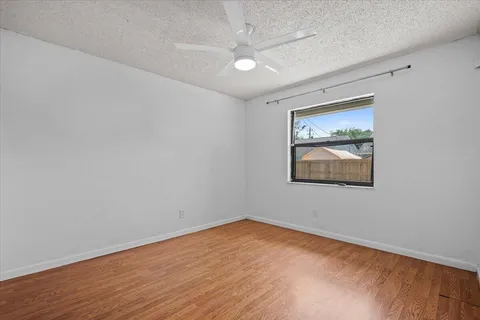 an empty room with a ceiling fan and window