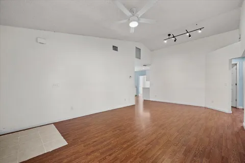 an empty room with wooden floor and ceiling fan