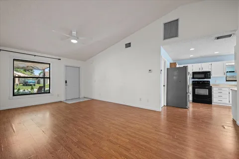 an empty room with wooden floor and windows