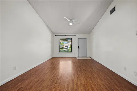 an empty room with wooden floor and windows