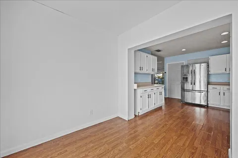 a kitchen with white cabinets and wooden floor