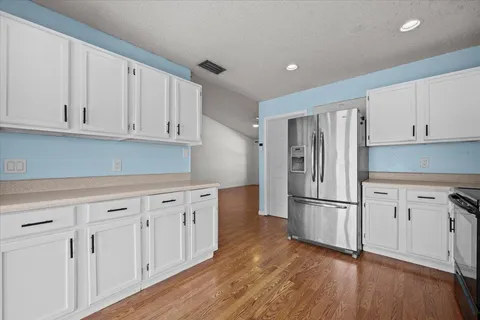 a kitchen with white cabinets white stainless steel appliances and wooden floors