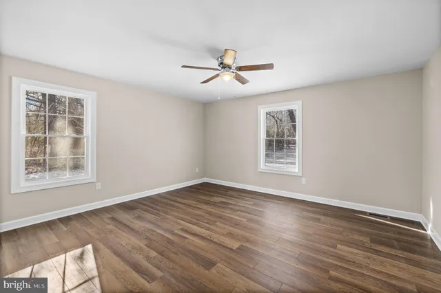a view of empty room with wooden floor and fan