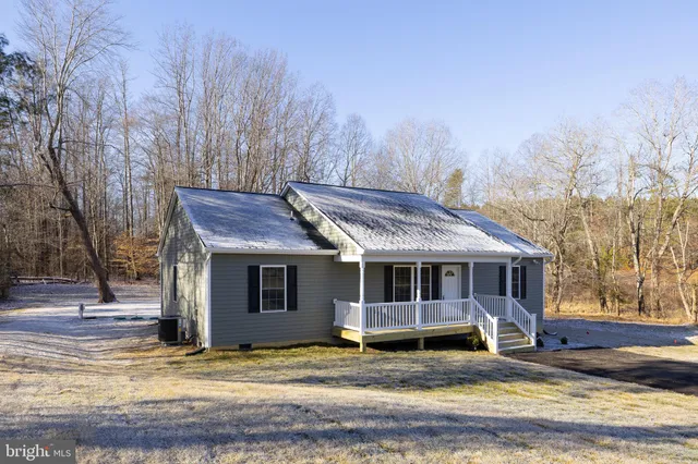 a view of a house with a small yard and large trees