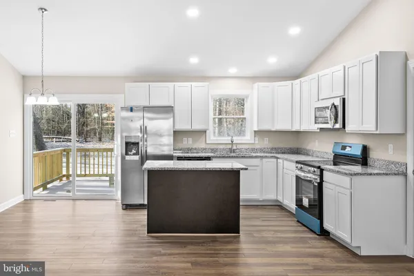 a kitchen with stainless steel appliances granite countertop a stove top oven a sink dishwasher a refrigerator and white cabinets with wooden floor