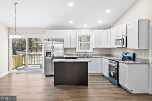 a kitchen with stainless steel appliances granite countertop a stove top oven a sink dishwasher a refrigerator and white cabinets with wooden floor
