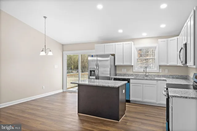 a kitchen with kitchen island granite countertop a sink cabinets and wooden floor