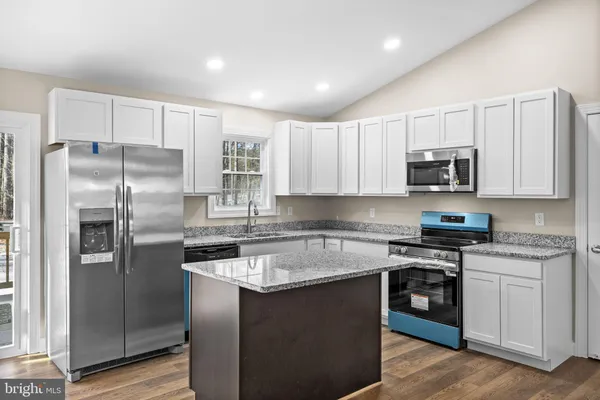 a kitchen with stainless steel appliances granite countertop a stove top oven a refrigerator and white cabinets