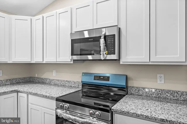 a kitchen with granite countertop white cabinets and stainless steel appliances