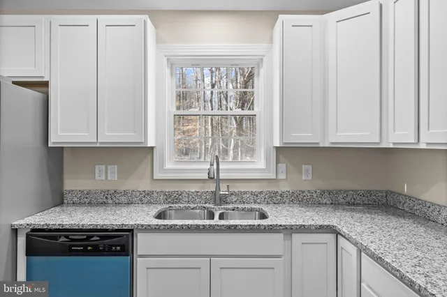 a kitchen with granite countertop white cabinets and a sink