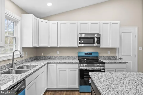 a kitchen with granite countertop a stove sink and cabinets