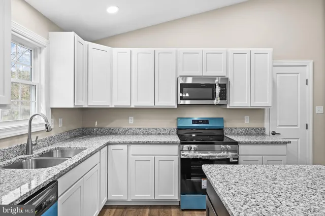 a kitchen with granite countertop a stove sink and cabinets