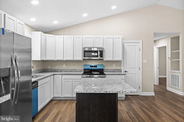 a kitchen with stainless steel appliances granite countertop a refrigerator a stove and a sink