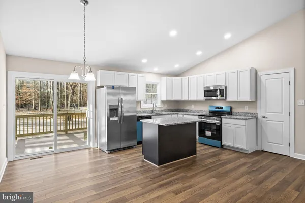 a kitchen with stainless steel appliances granite countertop a refrigerator a sink dishwasher a stove and white cabinets with wooden floor