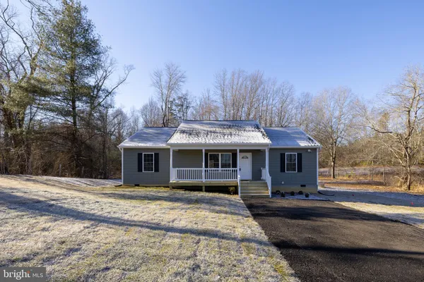a front view of a house with a garden and trees