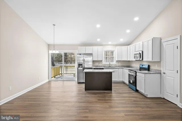 a large kitchen with kitchen island a large counter top space a sink stainless steel appliances and cabinets