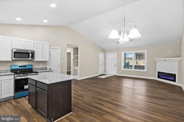 a kitchen with stainless steel appliances granite countertop a stove top oven a sink dishwasher and a microwave with wooden floor