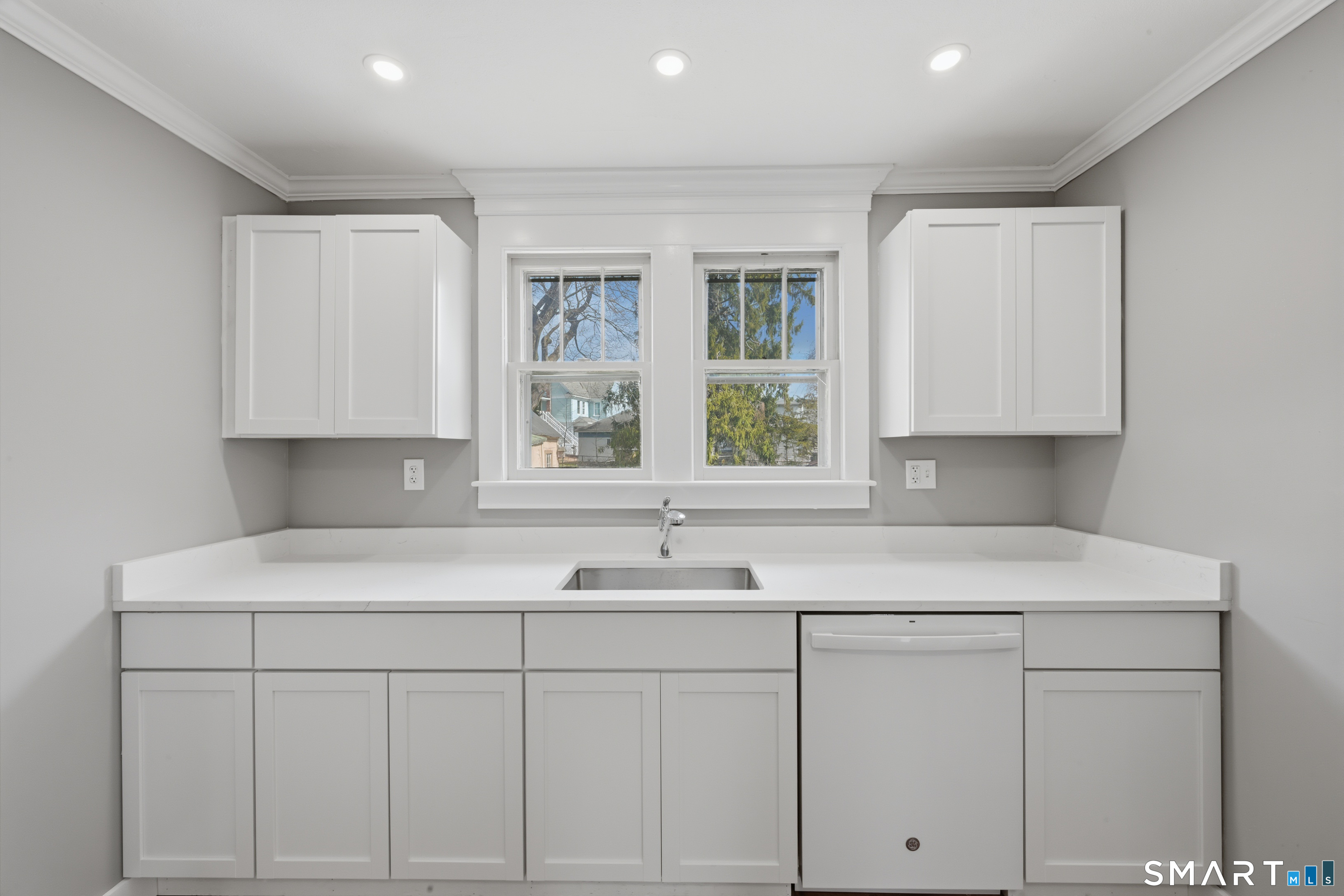 a kitchen with white cabinets and window
