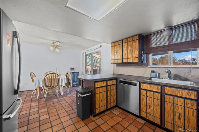 a kitchen with stainless steel appliances granite countertop a sink a stove a dining table and chairs