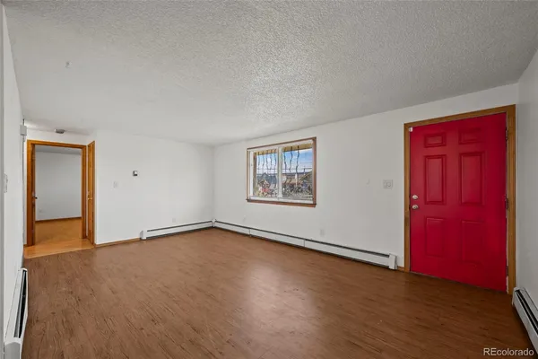 an empty room with wooden floor and windows