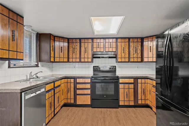 a kitchen with a sink appliances cabinets and a large window