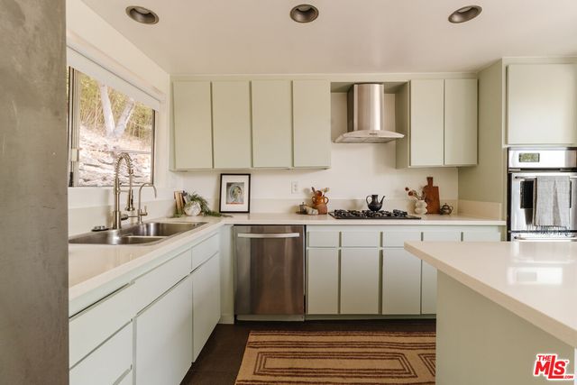 a kitchen with granite countertop a sink stainless steel appliances and cabinets