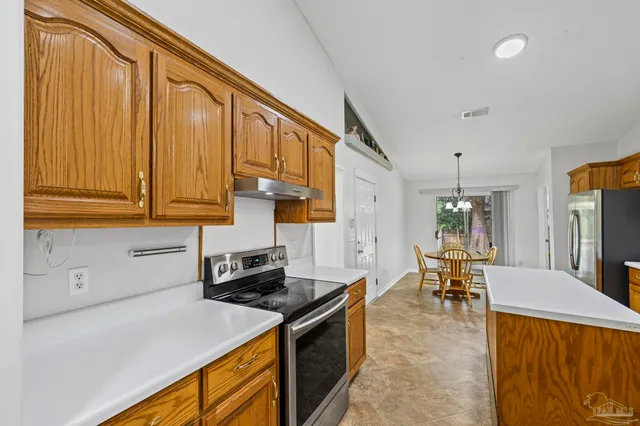 a kitchen with stainless steel appliances granite countertop a stove a sink dishwasher and a refrigerator with wooden cabinets