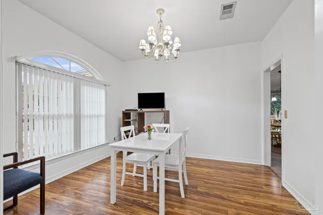 a dining room with wooden floor a chandelier a wooden table and chairs