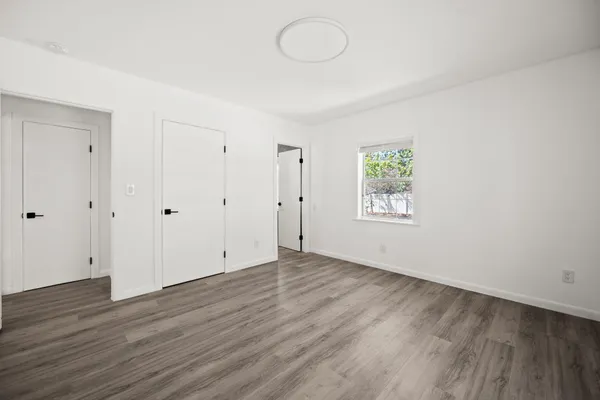 a view of an empty room with wooden floor and a window