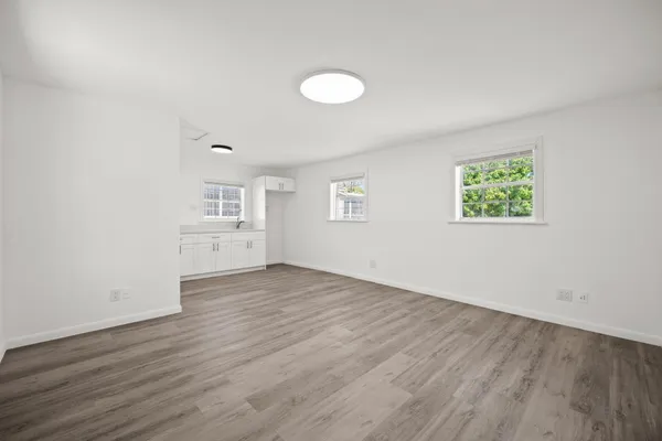 an empty room with wooden floor and windows
