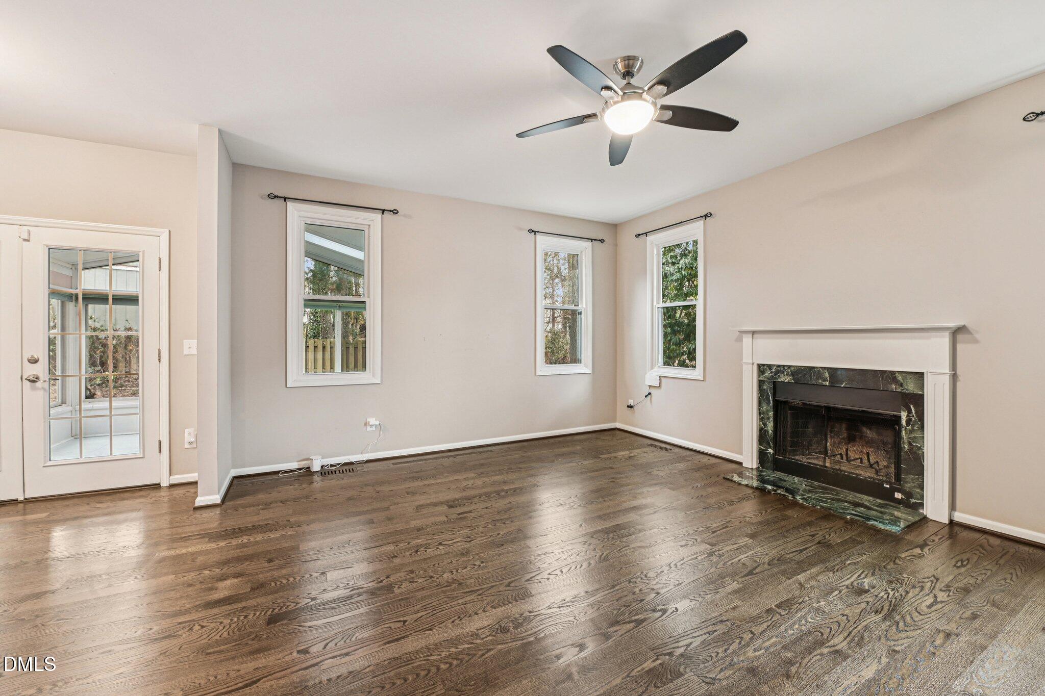 13100 Townfield Drive Raleigh, NC 27614 - Photo 7 of 31 an empty room with windows a fireplace and a chandelier fan